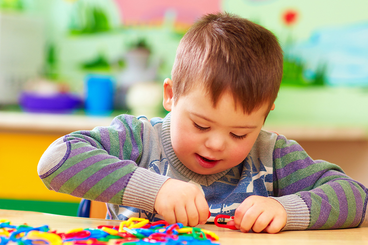 cute kid with down's syndrome playing in kindergarten